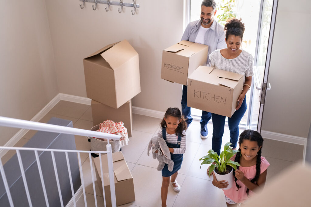 A family carrying boxes into their new home