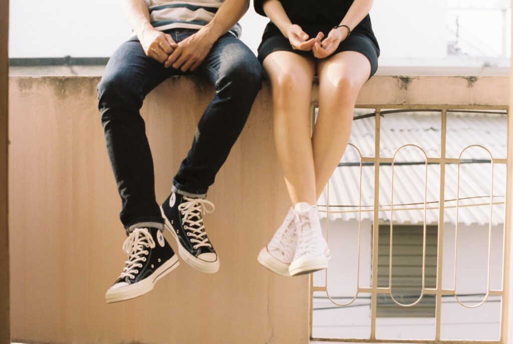 A couple sitting on a wall, cropped from the waist-down