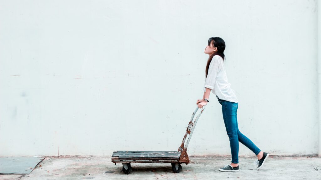 A woman pushing a dolly against a white background