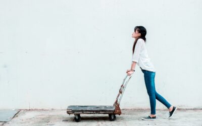 A woman pushing a dolly against a white background